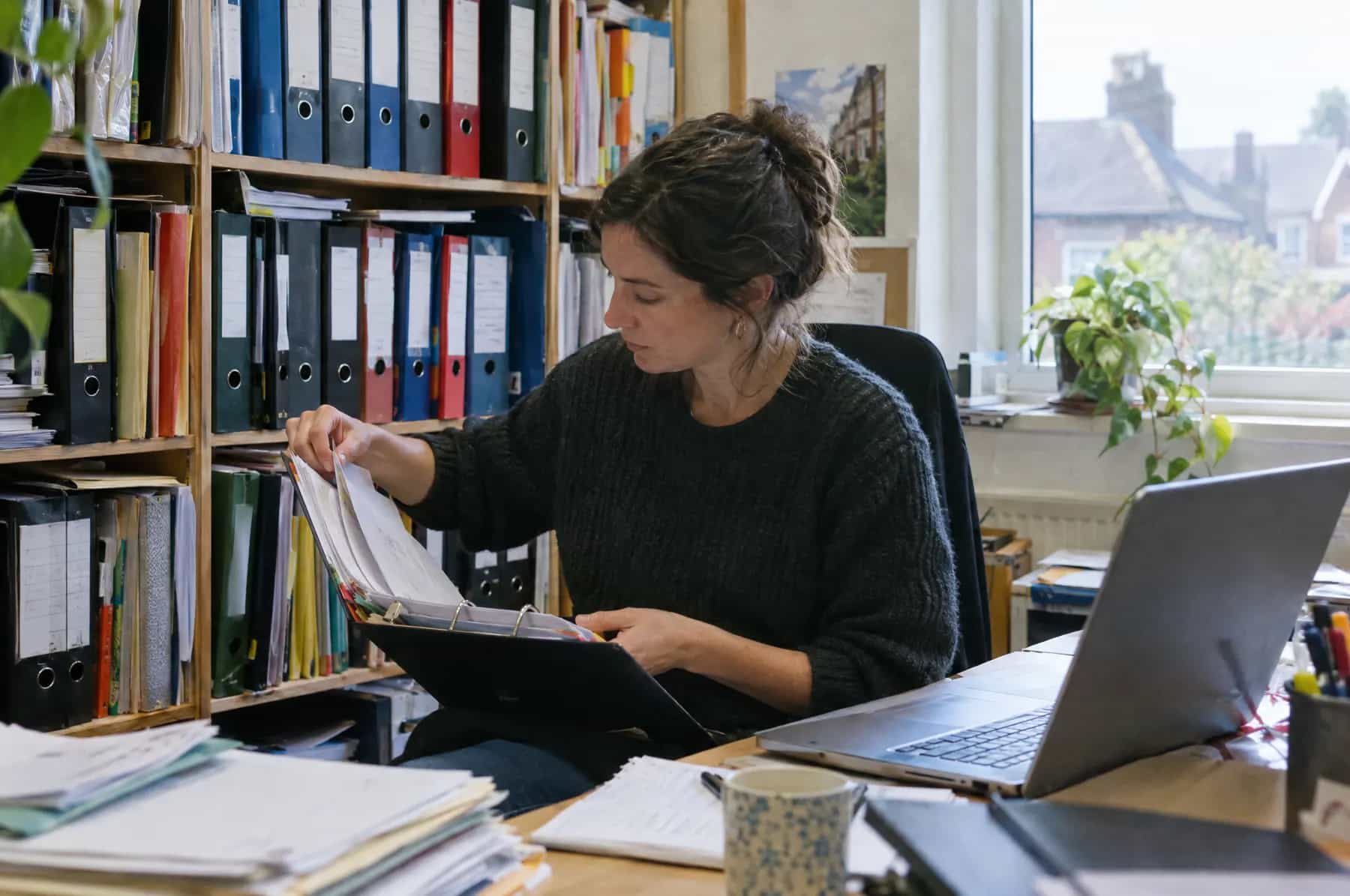 An office worker searching through an overstuffed ring binder for an answer