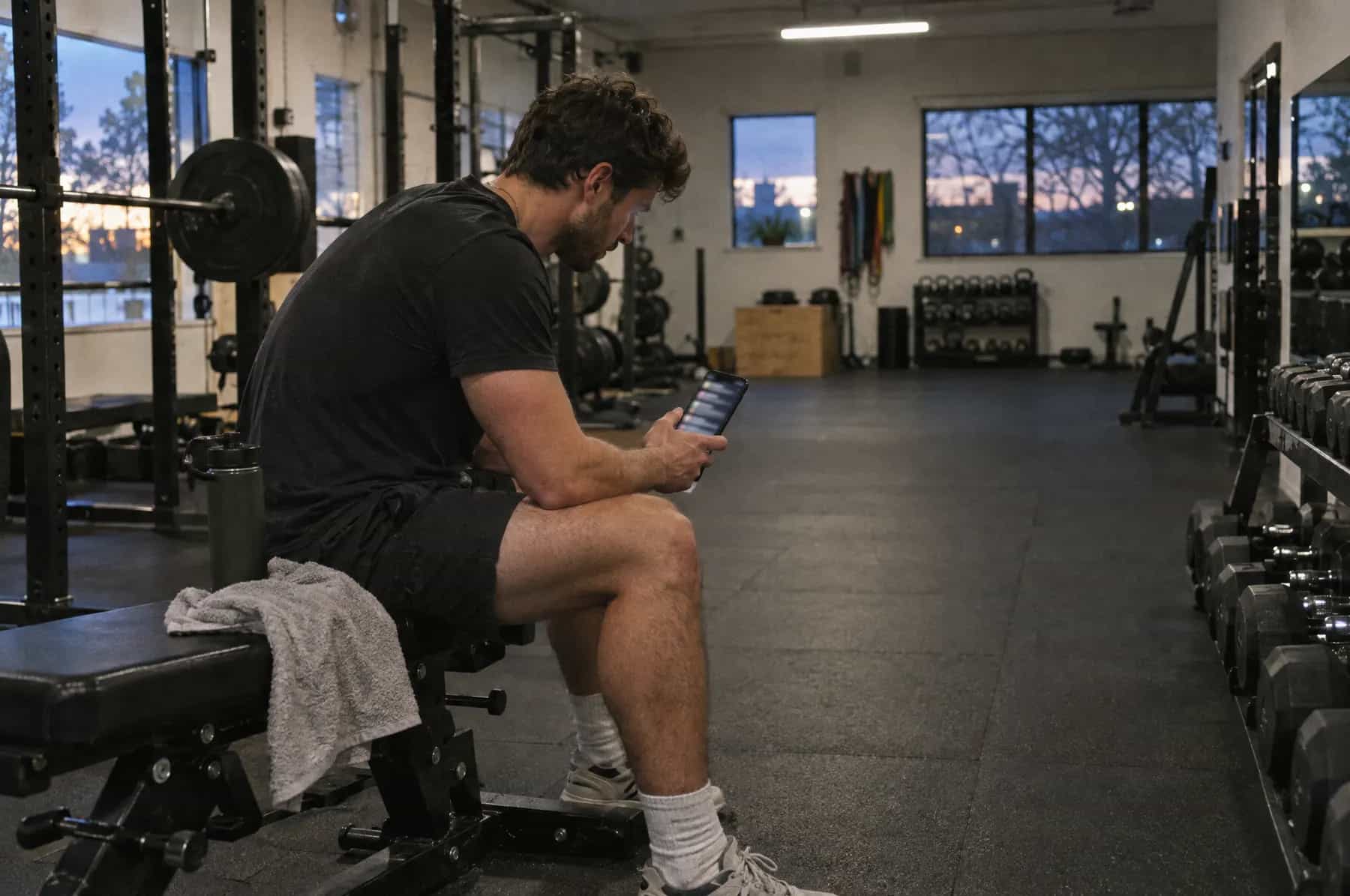 A personal trainer between sessions checking a phone full of new enquiries
